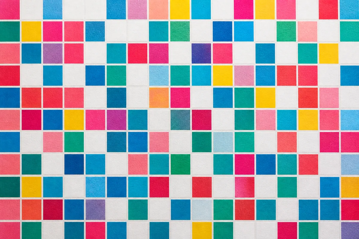 Mosaïque de petits carrés de couleur imprimés sur papier épais, cadrage à plat, lumière douce et rasante